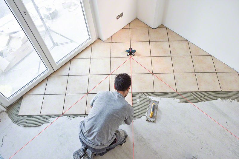 Profissional da construção civil usando nivelador a laser Bosch GTL 3 para nivelar o piso do chão.