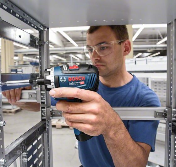 Funcionário da construção civil usando parafusadeira 12V para parafusar metal.