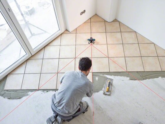 Profissional da construção civil usando nivelador a laser Bosch GTL 3 para nivelar o piso do chão.