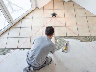 Profissional da construção civil usando nivelador a laser Bosch GTL 3 para nivelar o piso do chão.