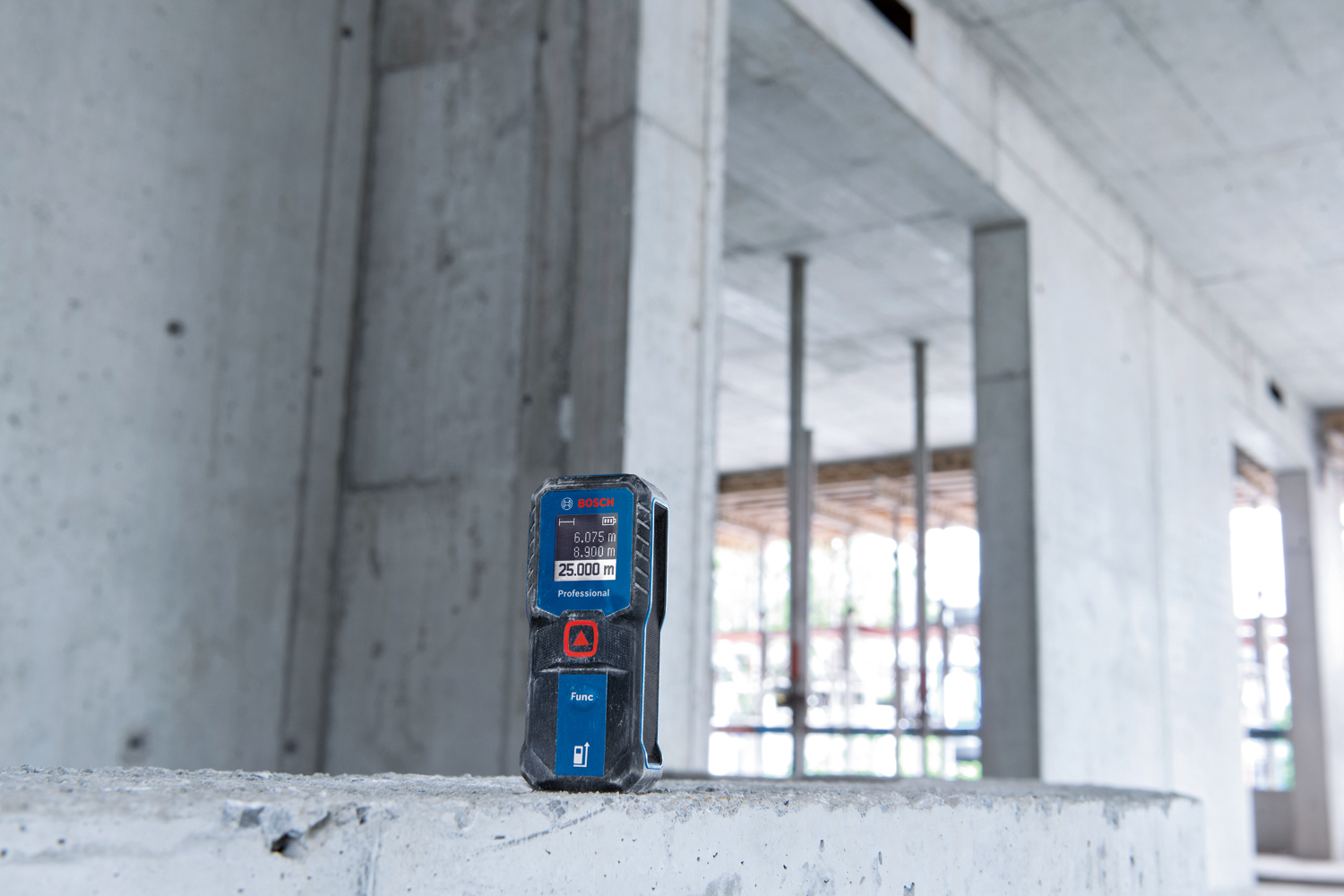 trena laser bosch GLM 30-23 em cima de um muro de concreto, dentro de uma construção inacabada